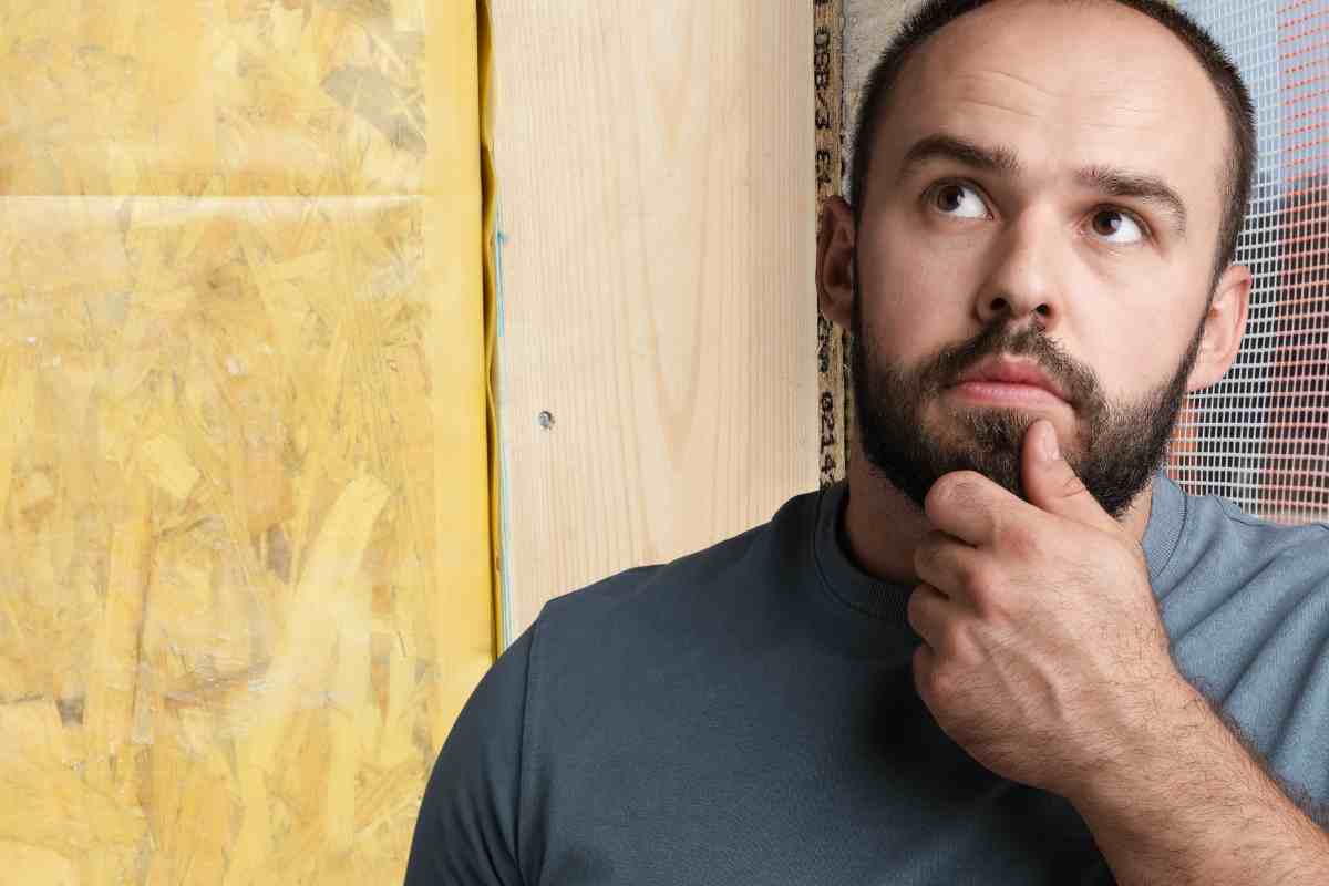 uomo pensieroso davanti a un cappotto termico