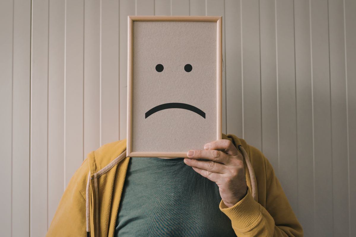 uomo con cartello in faccia con espressione triste