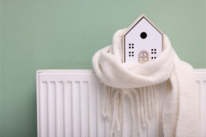 rappresentazione di una piccola casa posta su un termosifone avvolta da una sciarpa