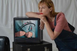 donna appoggiata su una vecchia tv che trasmette Il Paradiso delle Signore