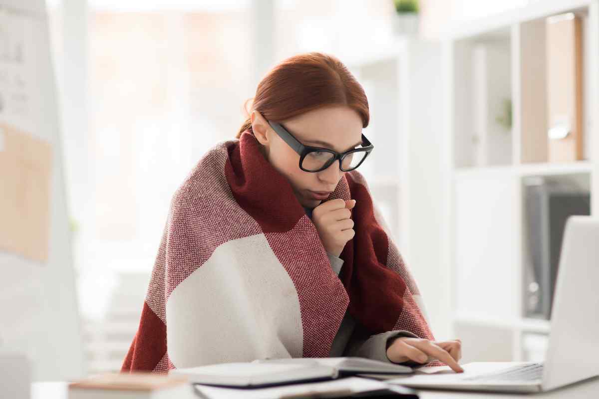 donna lavora al pc coprendosi per il freddo