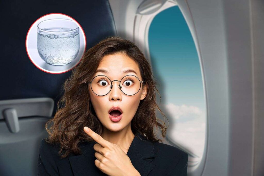 finestrino dell'aereo, bicchiere di acqua frizzante in icona rossa e donna sorpresa