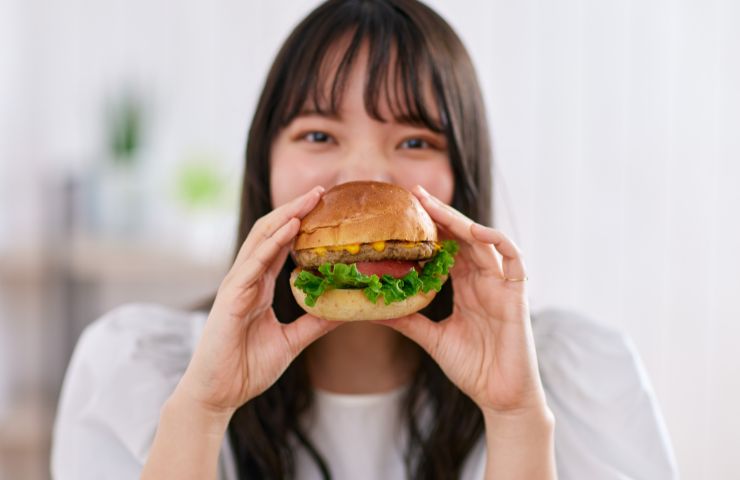 donna che mangia panino con hamburger e insalata