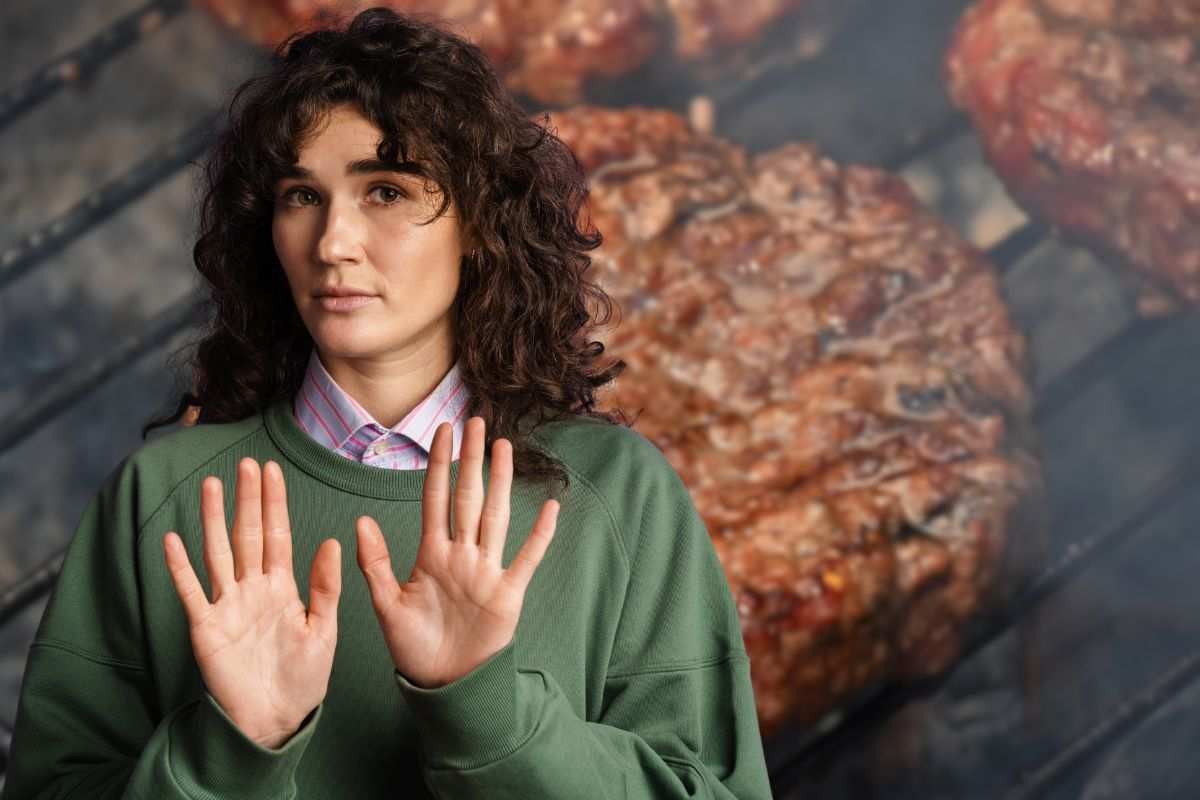 hamburger sulla piastra e donna che fa stop con le mani