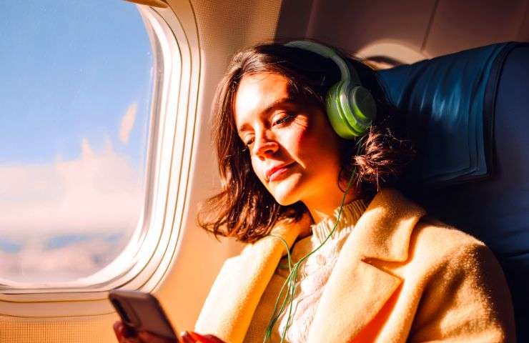 donna in aereo che ascolta musica con cuffie